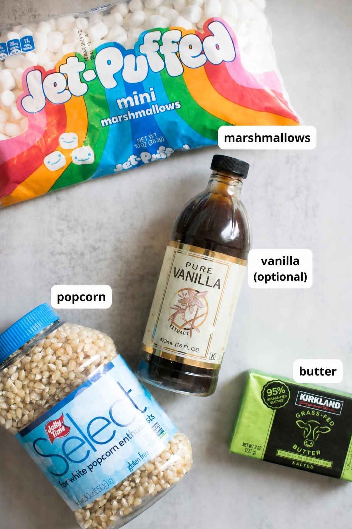 Ingredients for 3 ingredient popcorn balls on a tray: marshmallows, popcorn, vanilla and butter.
