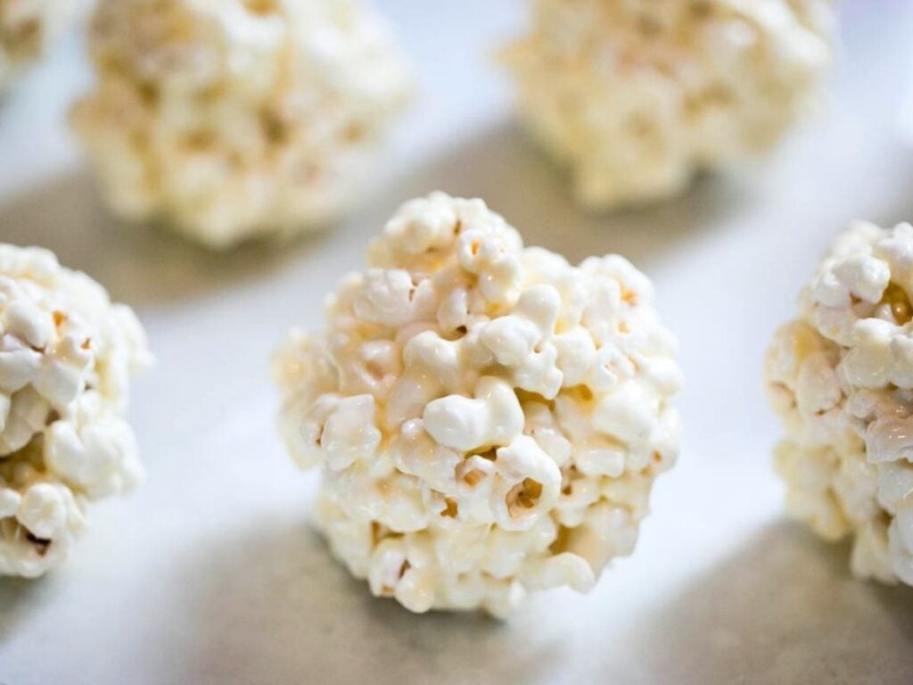 5 homemade popcorn balls sitting on a baking sheet.