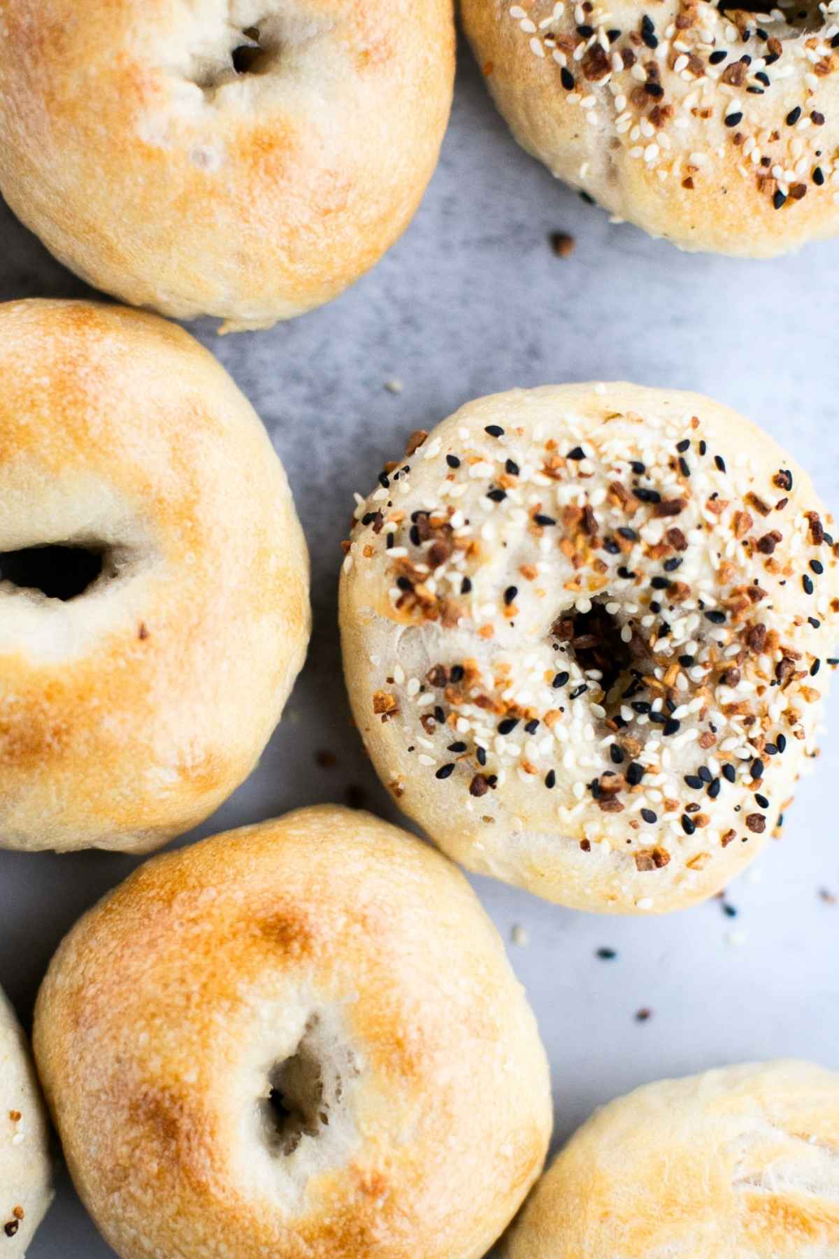 Six sourdough bagels on a tray.