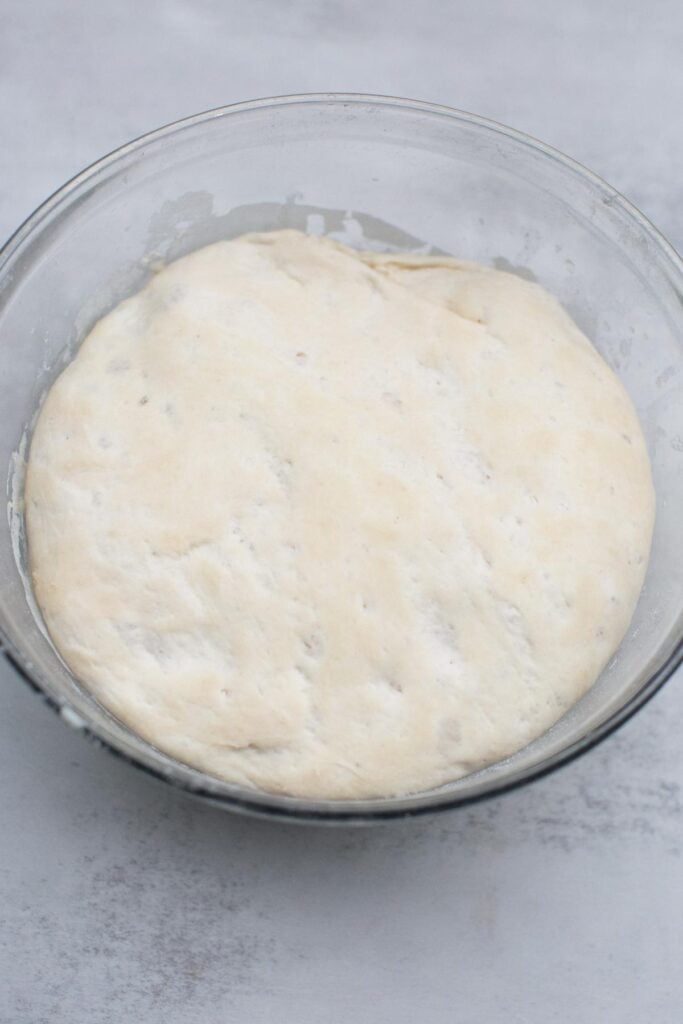 Sourdough bagel dough in a bowl after it has been fermented, sitting on a counter.