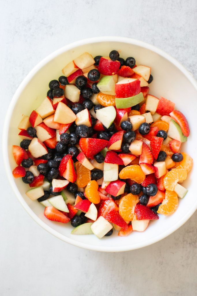 chick fil a fruit cup salad in a bowl with strawberries, blueberries, apples and orange slices