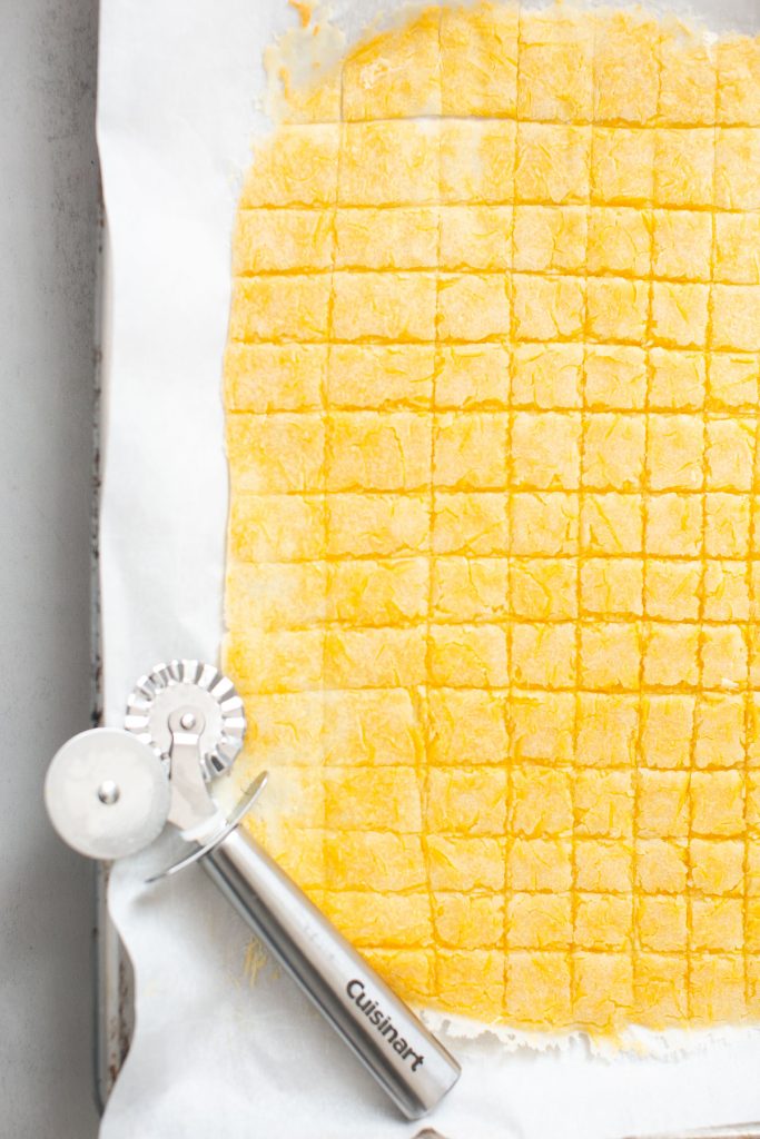 sourdough discard cheddar crackers being cut with a pastry cutter