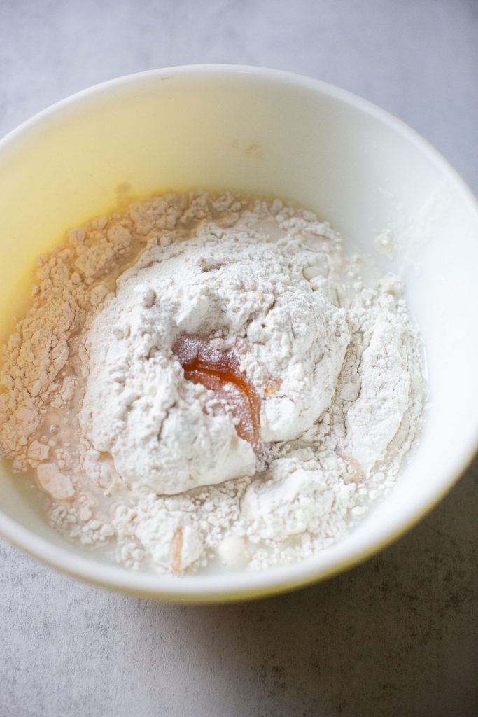 sourdough focaccia ingredients in a bowl: honey, flour, salt, and sourdough starter
