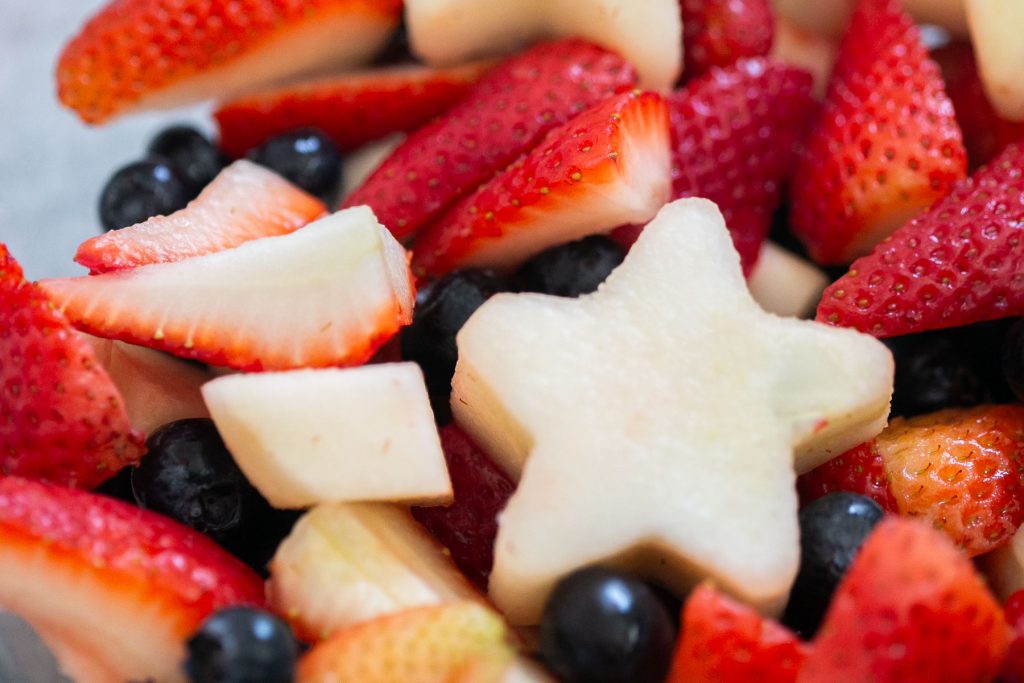 red white and blue fruit salad with star shaped pears, blueberries and strawberries.