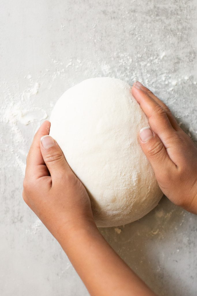 sourdough bread dough being shaped into a loaf