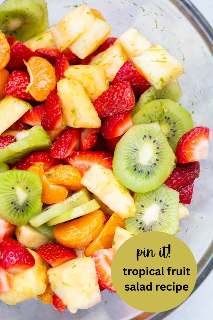 a pinterest pin with tropical fruit salad: kiwi, pineapple, oranges, strawberries and lime zest