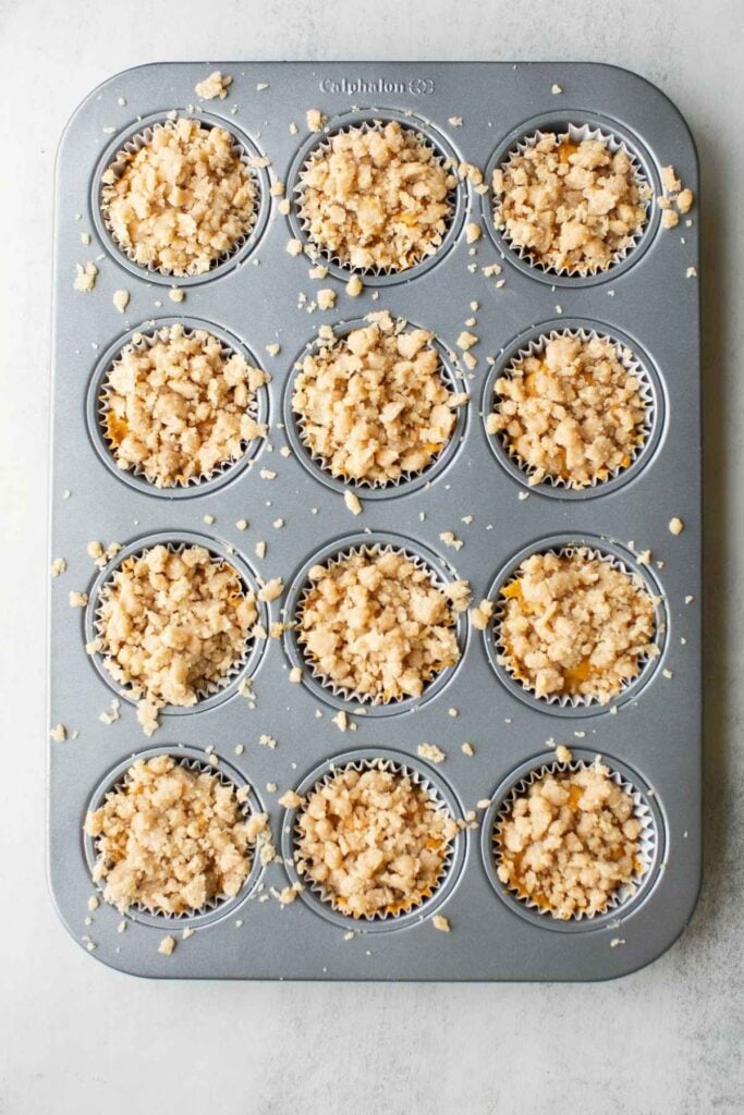 sourdough pumpkin streusel muffins in a muffin tin on a counter.