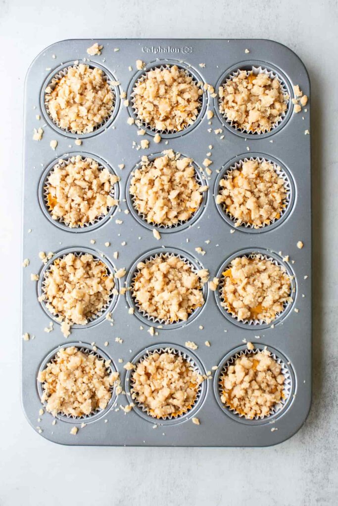 pumpkin streusel muffins in a muffin tin with streusel sprinkled on top of each muffin