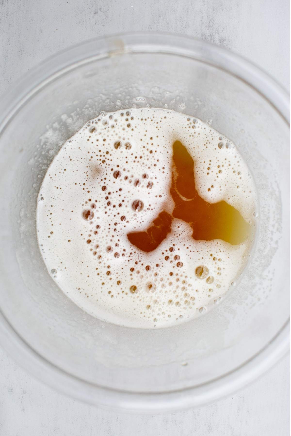 A clear bowl with browned butter cooling inside of it.