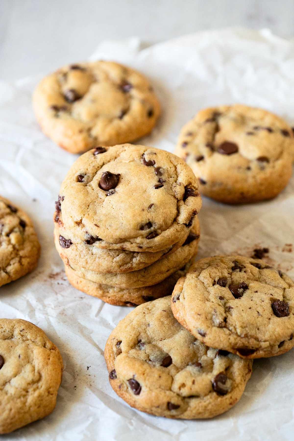 A stack of browned butter sourdough discard chocolate chip cookies sitting on a piece of parchment paper.