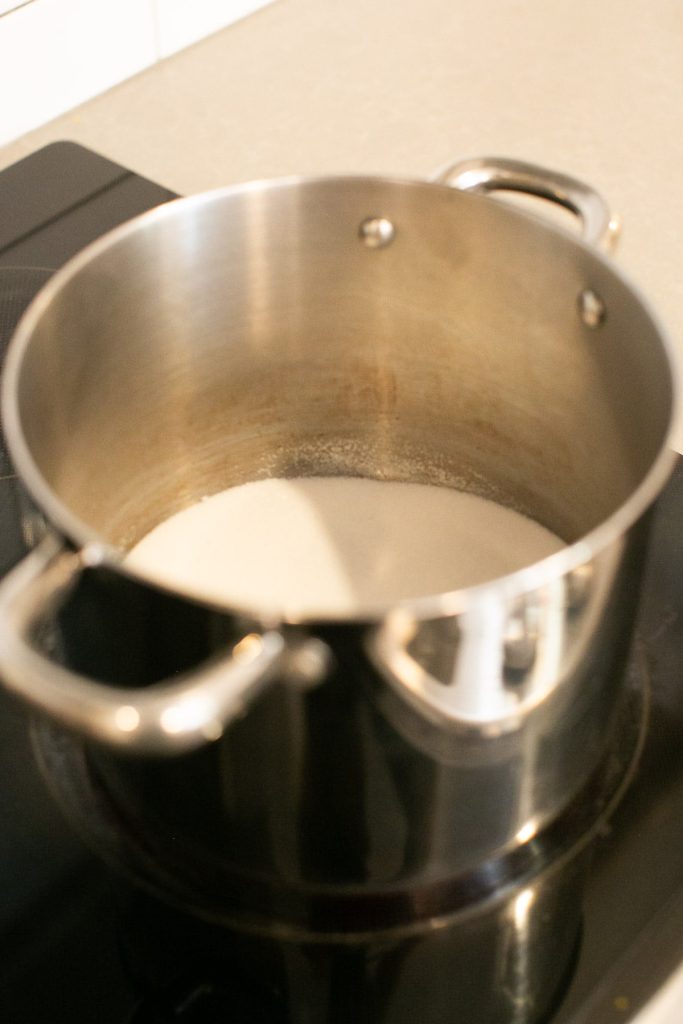 sugar in a deep pot being cooked over medium heat for caramel sauce