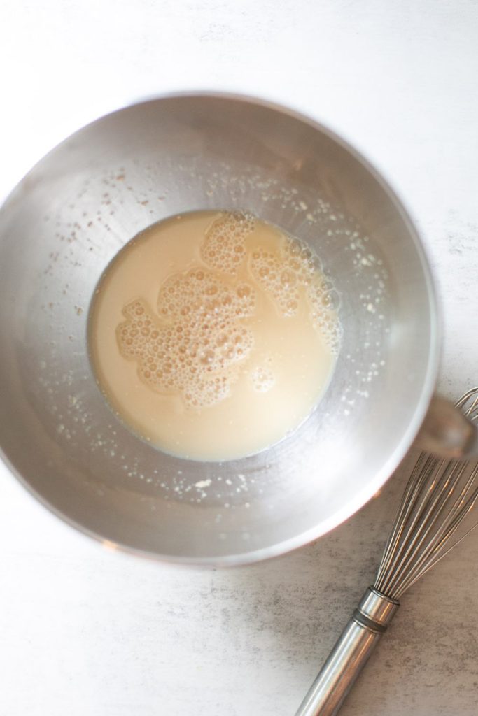 instant yeast, warm water, and honey mixed together in the bowl of a stand mixer