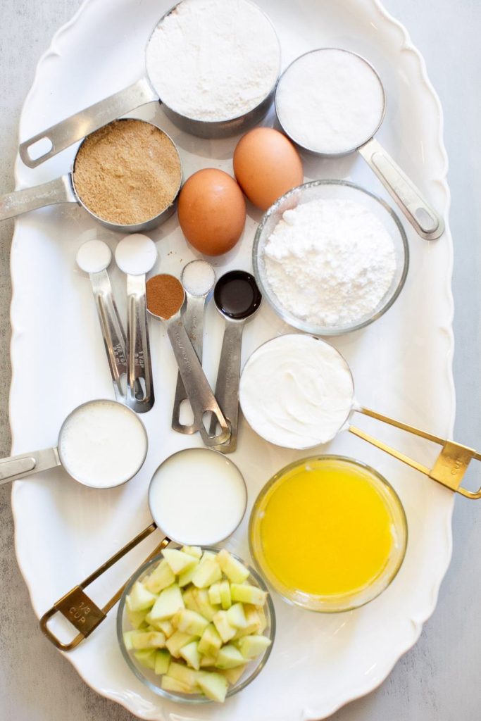ingredients for apple crumble muffins on plate: eggs, diced green apples, sour cream, flour, brown sugar and spices