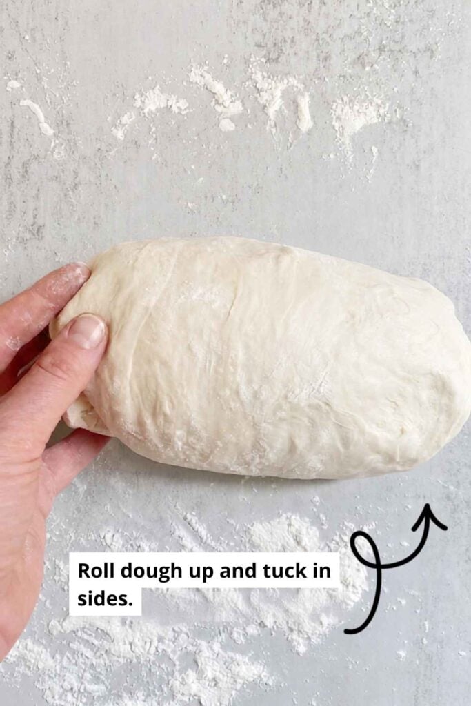Sourdough sandwich bread dough rolled into a log on a table.