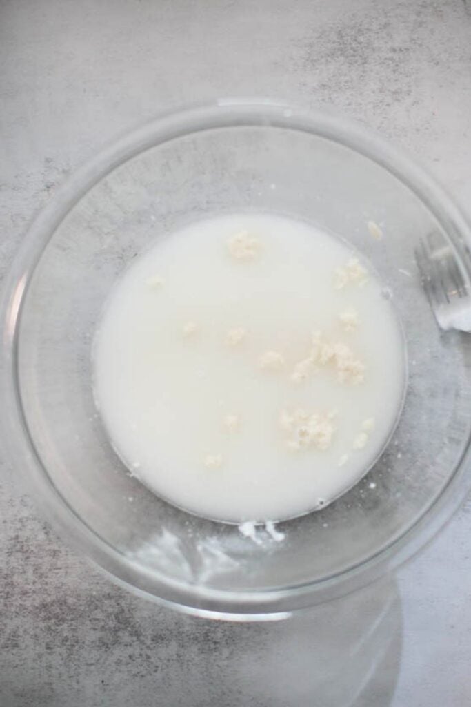 Active sourdough starter mixed with water in a large bowl for sourdough sandwich bread.