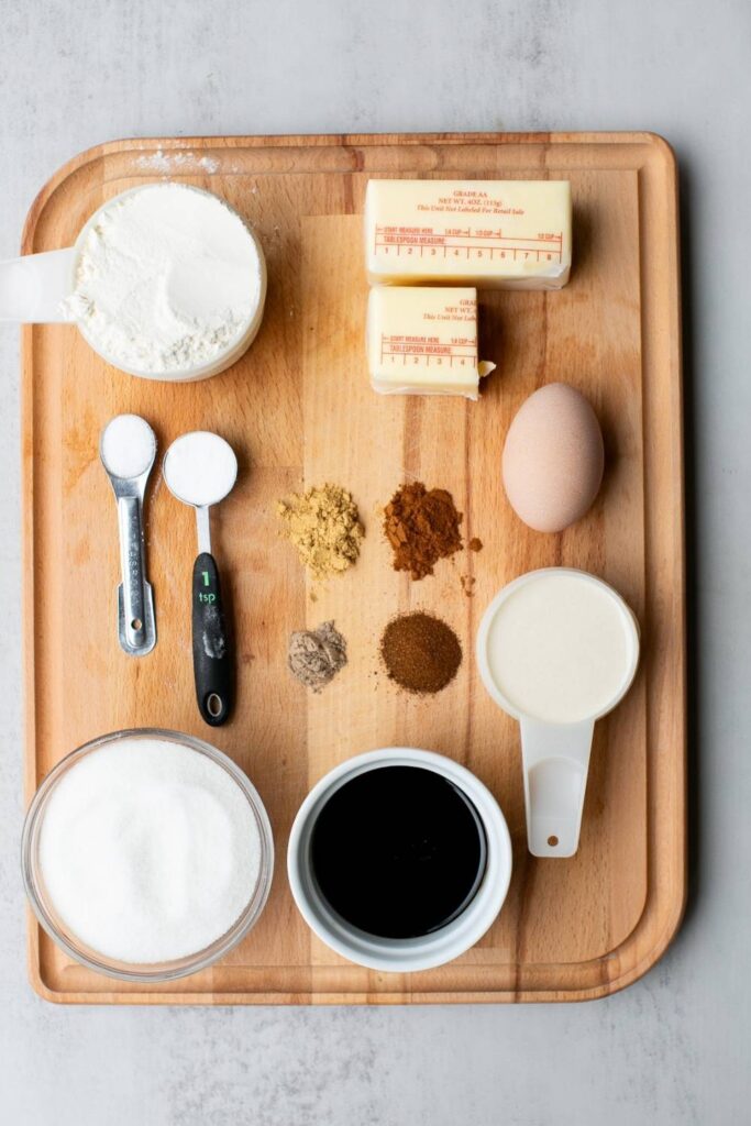 ingredients for sourdough molasses gingerbread cookies on a tray: egg, discard, flour, cinnamon, molasses, and ground ginger, butter and sugar