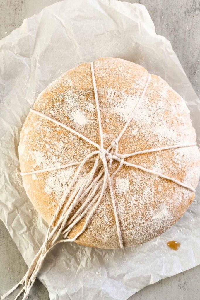A loaf of sourdough bread with twine wrapped around it for a pumpkin shaped loaf.