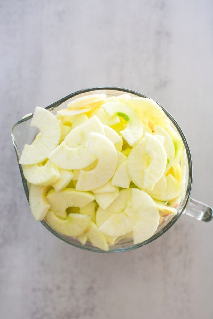 chopped up apples in a glass bowl on a counter.