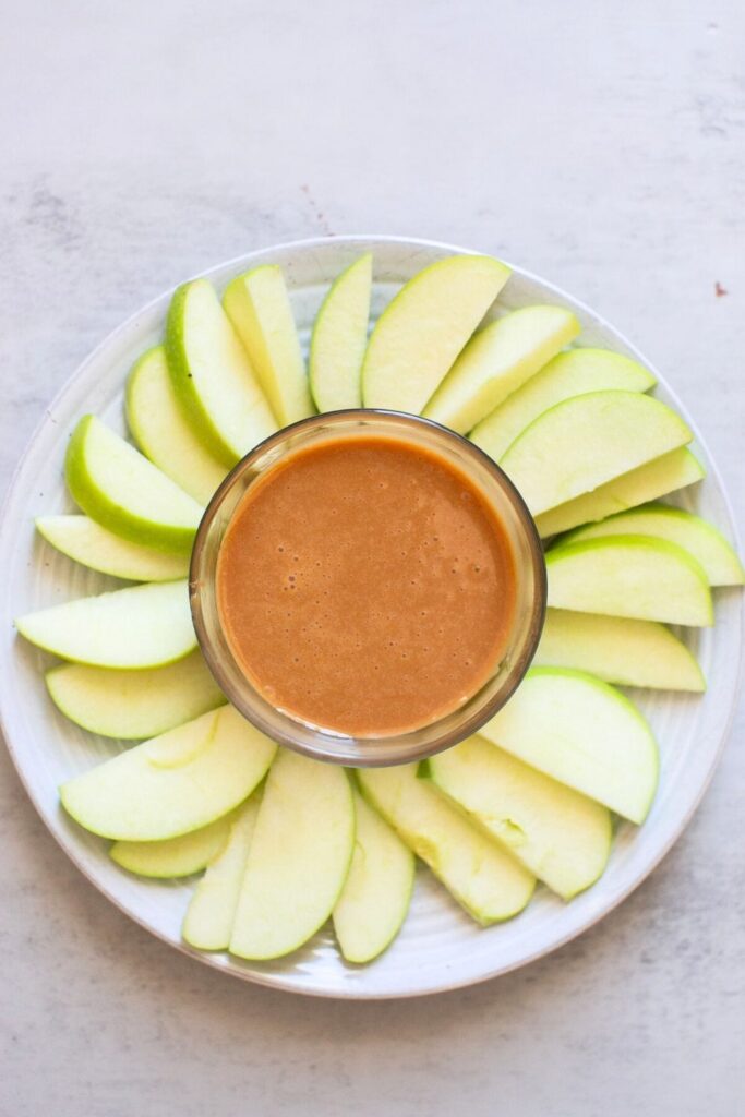 homemade caramel dip in a bowl with cut up slices of granny smith apples