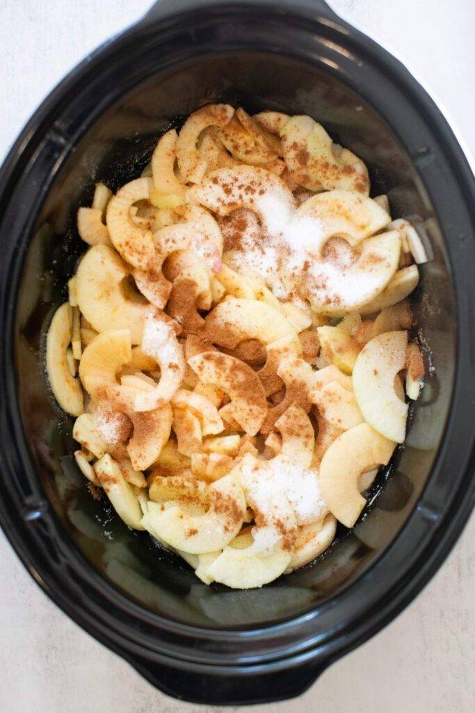 cinnamon, sugar, apples and water added to a crockpot to make applesauce