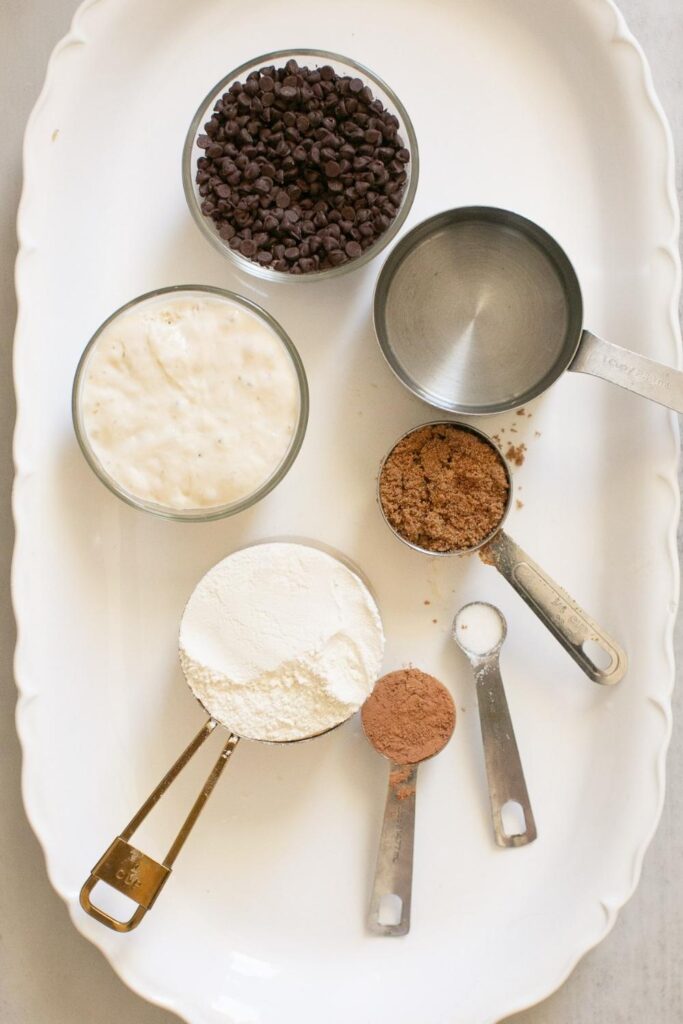 ingredients for double chocolate sourdough bagels: mini chocolate chips, water, sourdough starter, all purpose flour, brown sugar, cocoa powder and salt