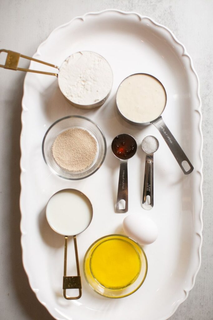 sourdough discard ingredients on a tray: honey, salt, melted butter, sourdough discard, all purpose flour, milk and egg