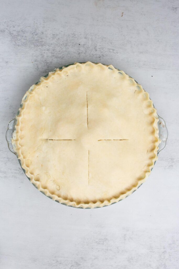 An 9 inch apple pie sitting on a countertop being being baked.