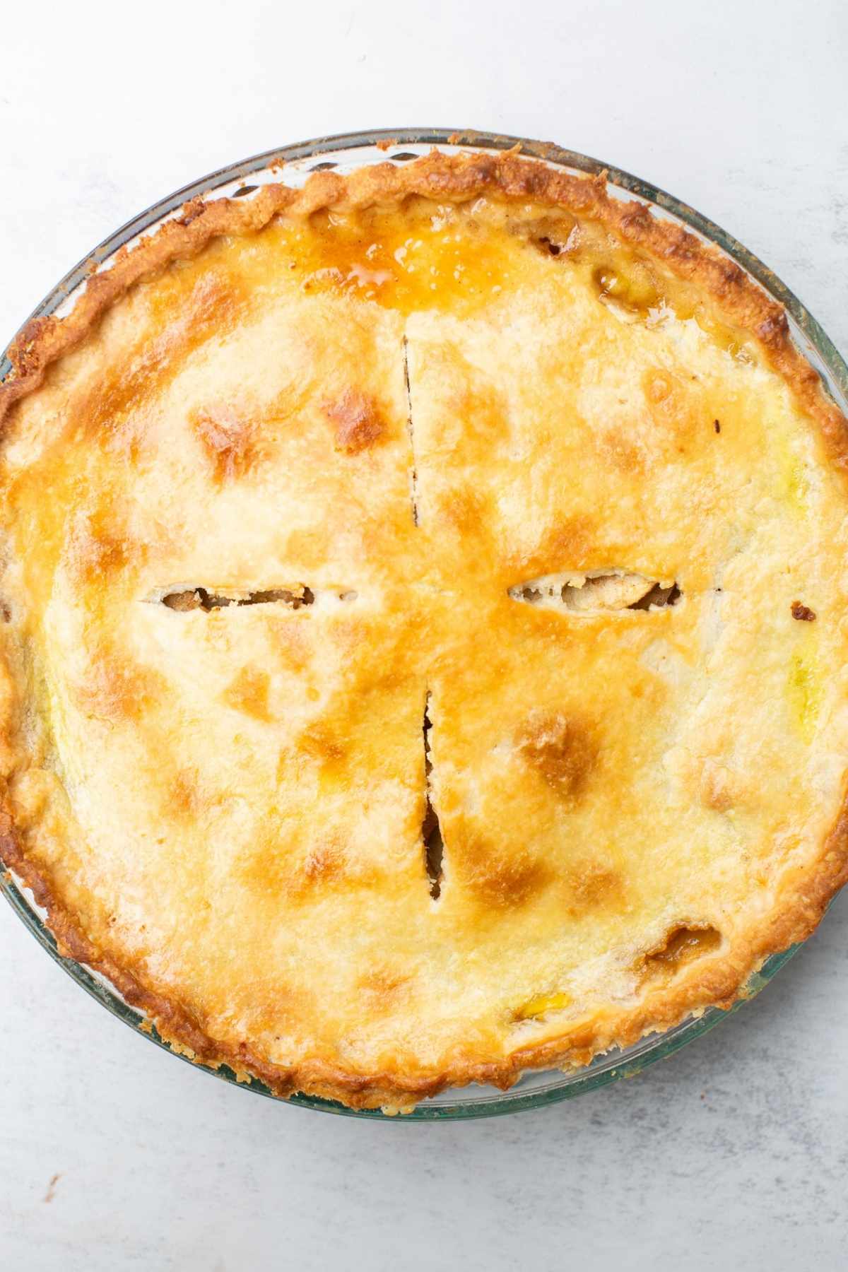 A flaky apple pie sitting on a pie crust