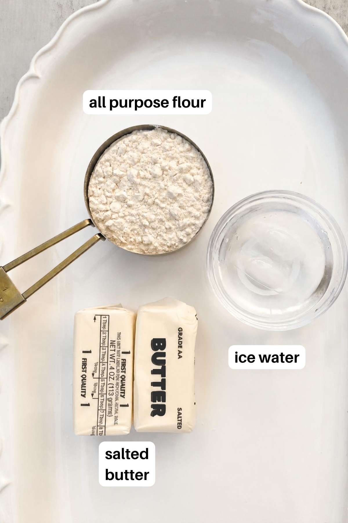 Ingredients for pie crust on a tray: flour, ice cold water, and salted butter.