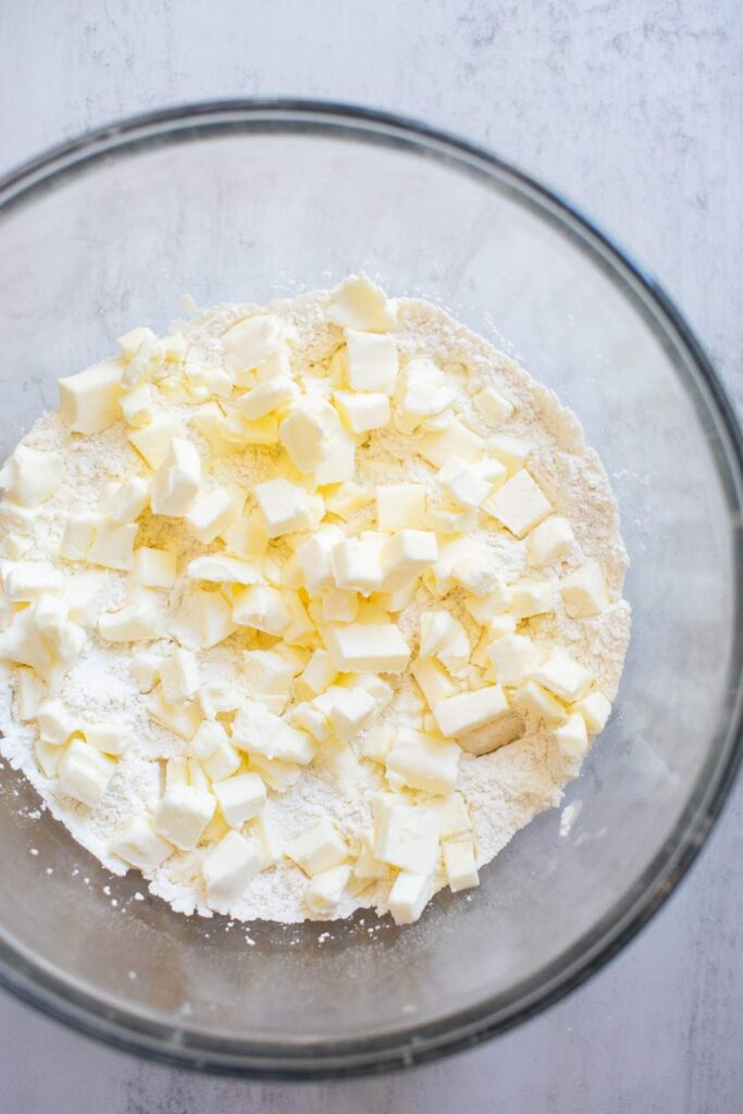 Cut up chunks of butter mixed with flour in a large bowl.