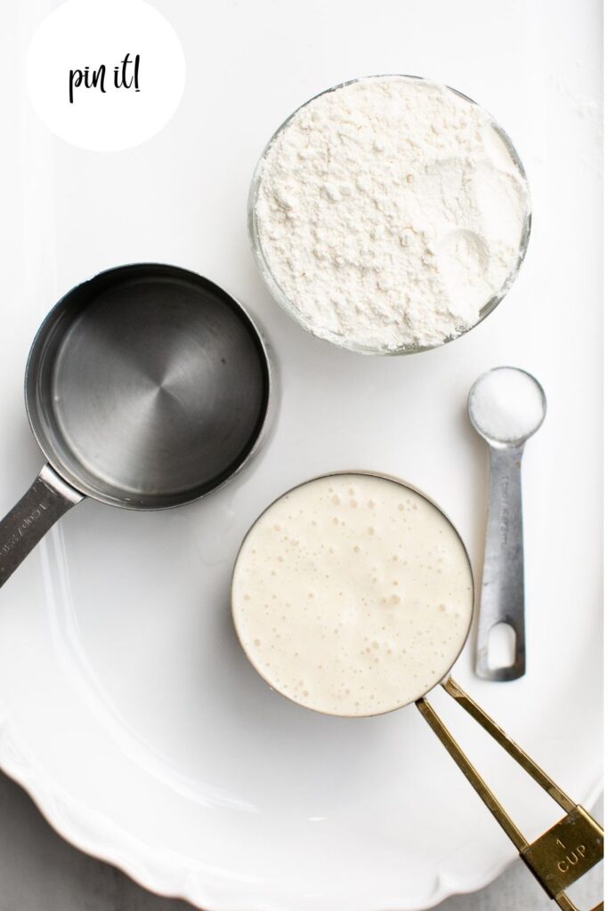 ingredients for sourdough unloaf bread on a tray: flour, sourdough starter, salt, filtered water
