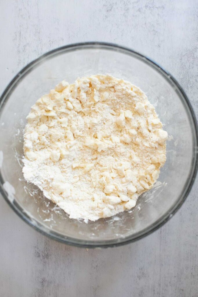 Pie crust dough being mixed together in a bowl.