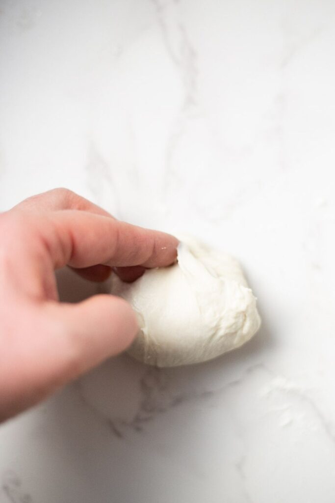 sourdough croissant bread roll dough being shaped into a roll