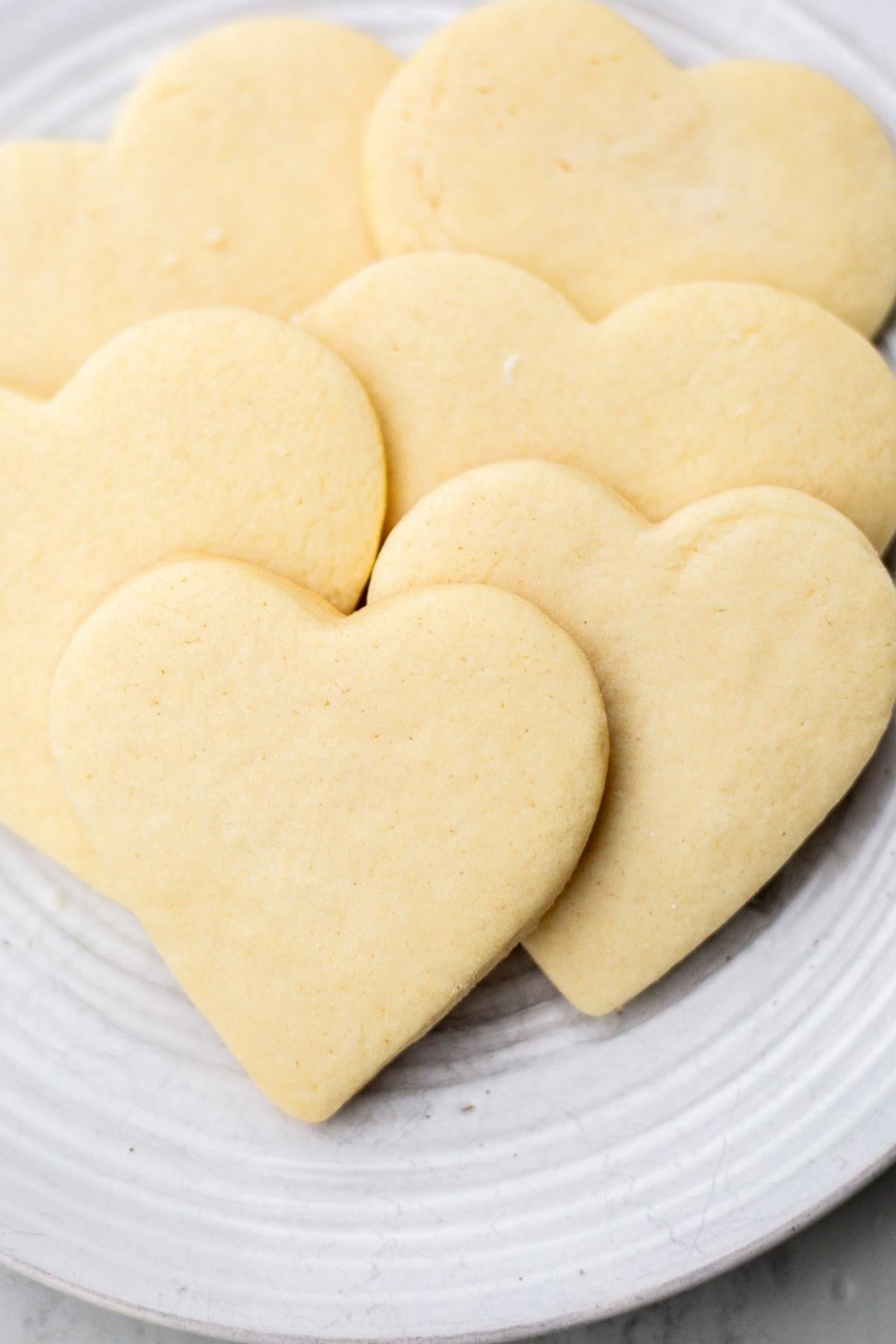 A stack of heart shaped sourdough discard sugar cookies on a plate.