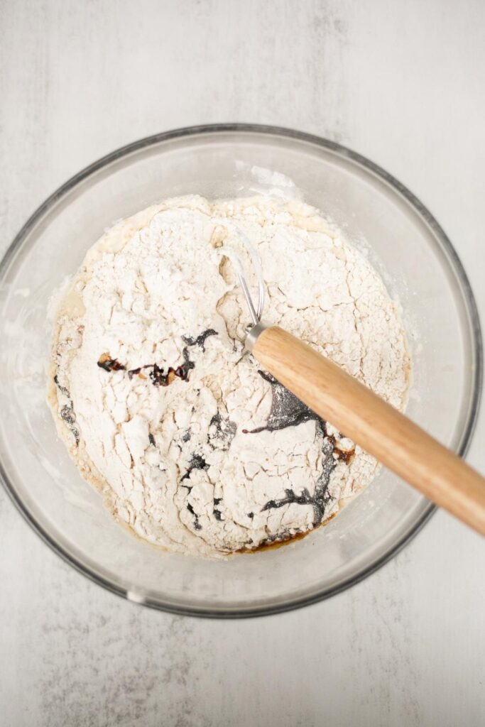 flour, water, molasses, salt and ginger mixed in a large bowl for sourdough gingerbread loaf
