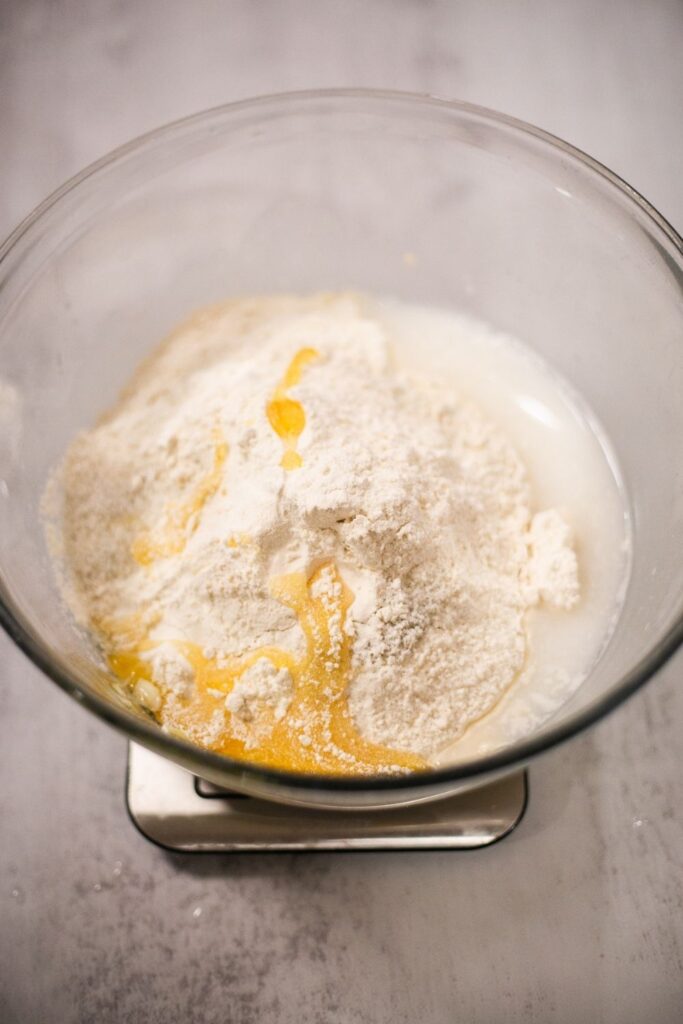 sourdough pretzel dough being mixed together in a bowl with active starter, honey, salt, and flour