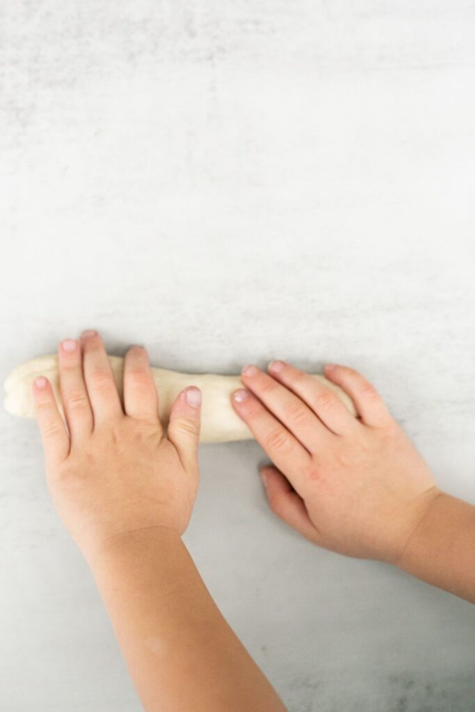 sourdough pretzel dough being shaped by two hands