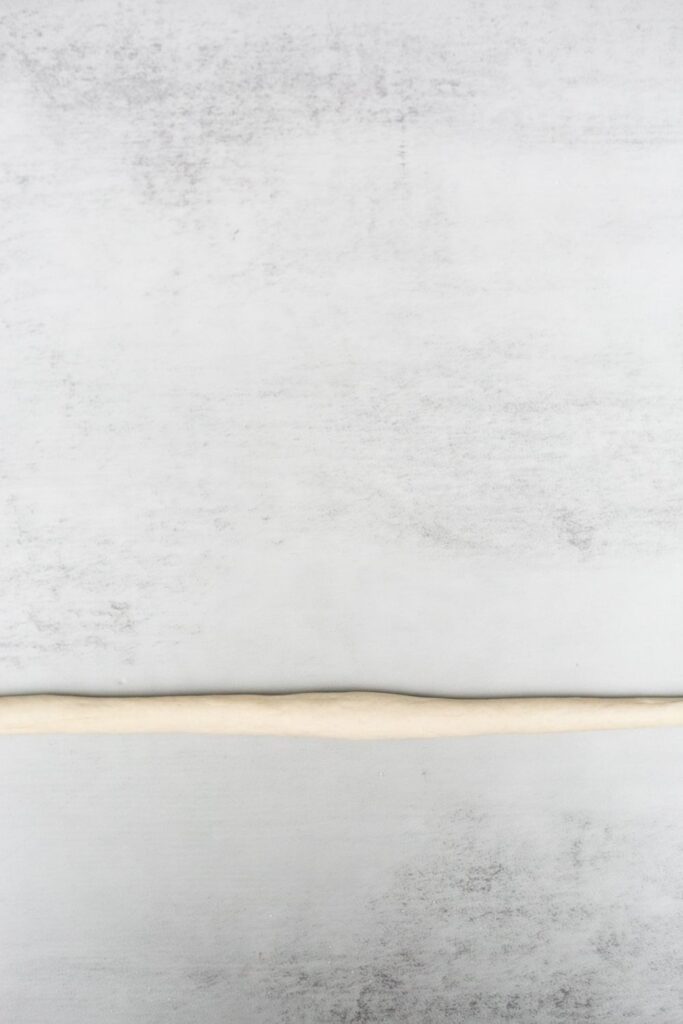 sourdough pretzel dough rolled out in a long piece of dough