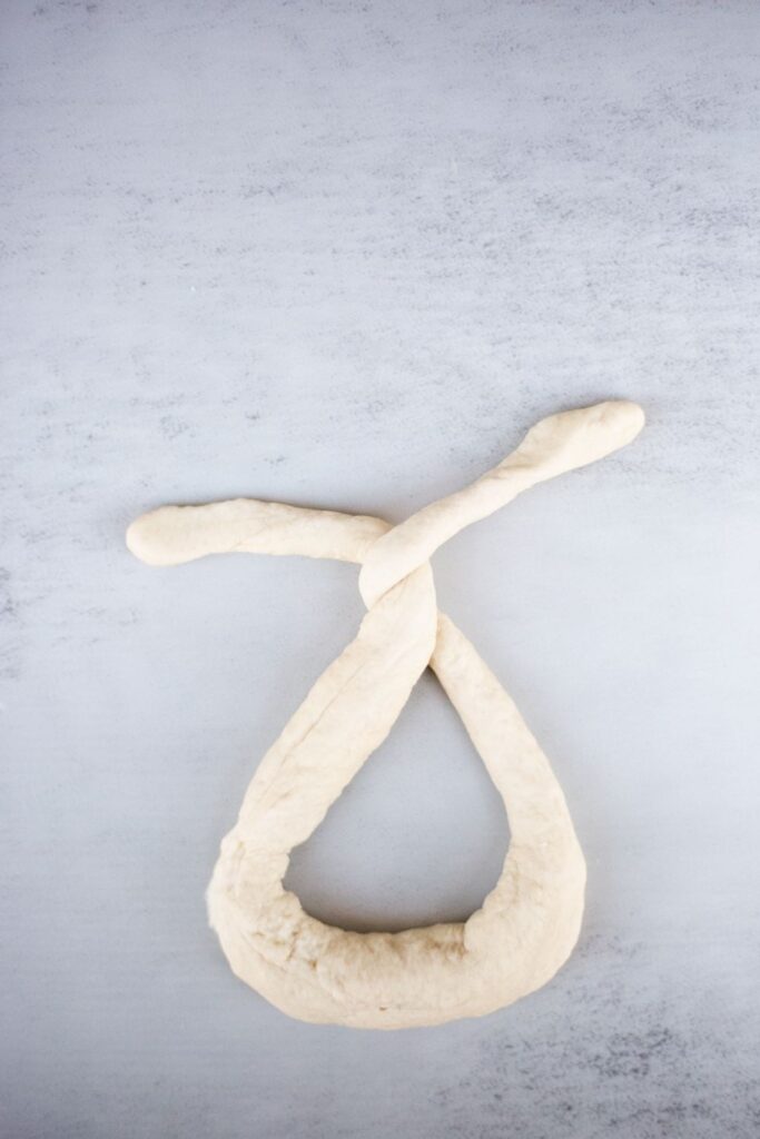 sourdough pretzel dough being twisted before baking