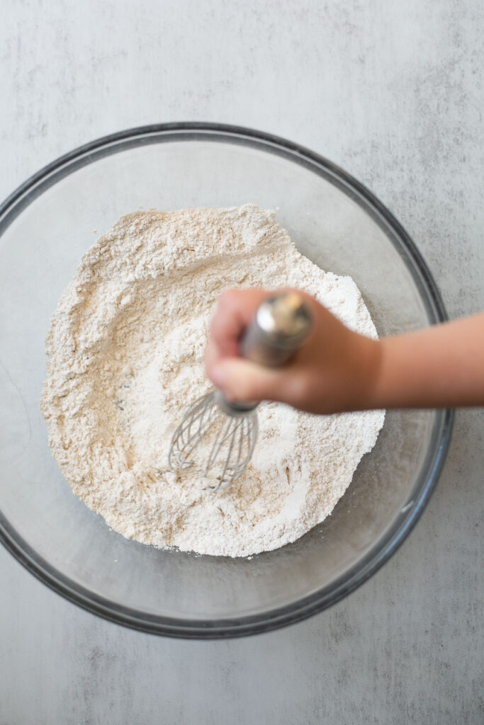 flour, salt, nutmeg, and cinnamon being mixed together in a large bowl for sourdough discard banana muffins