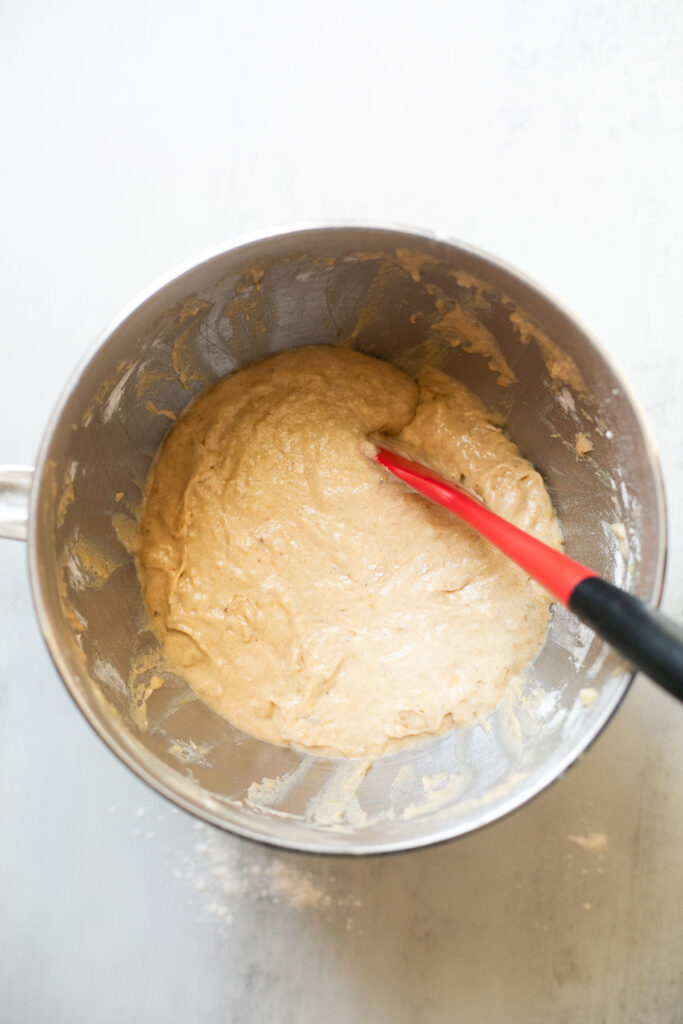 wet and dry ingredients being mixed together in a large bowl for sourdough banana muffins