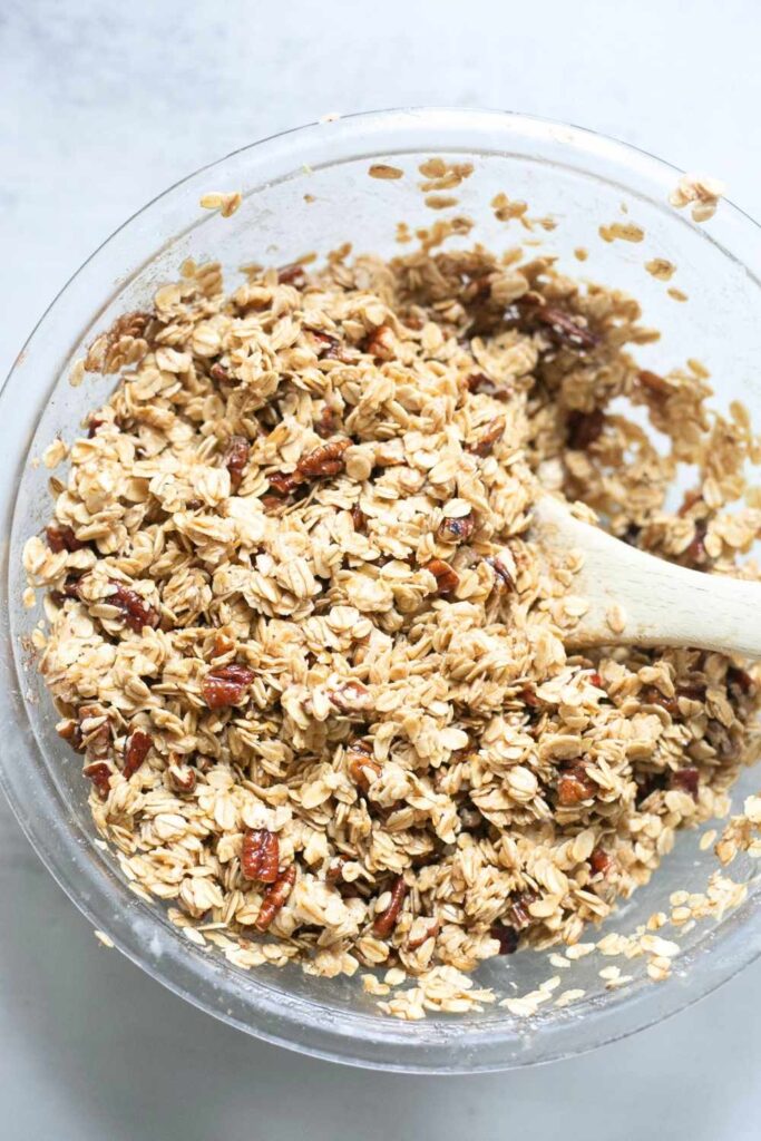 sourdough discard granola being mixed in a large bowl with honey