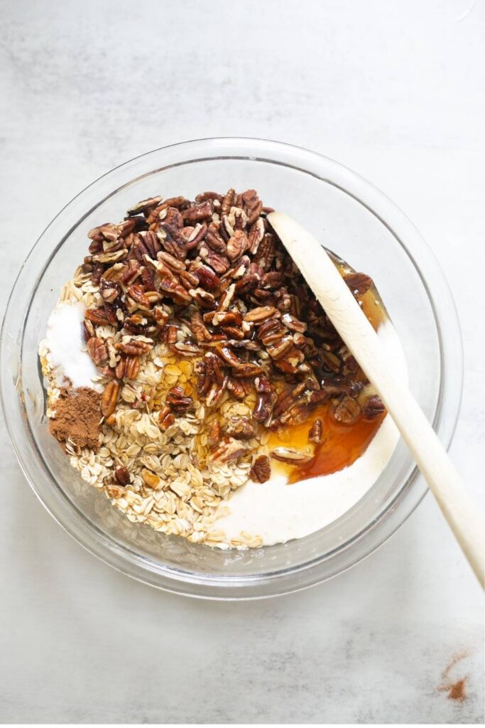 sourdough discard granola being mixed in a large bowl with honey