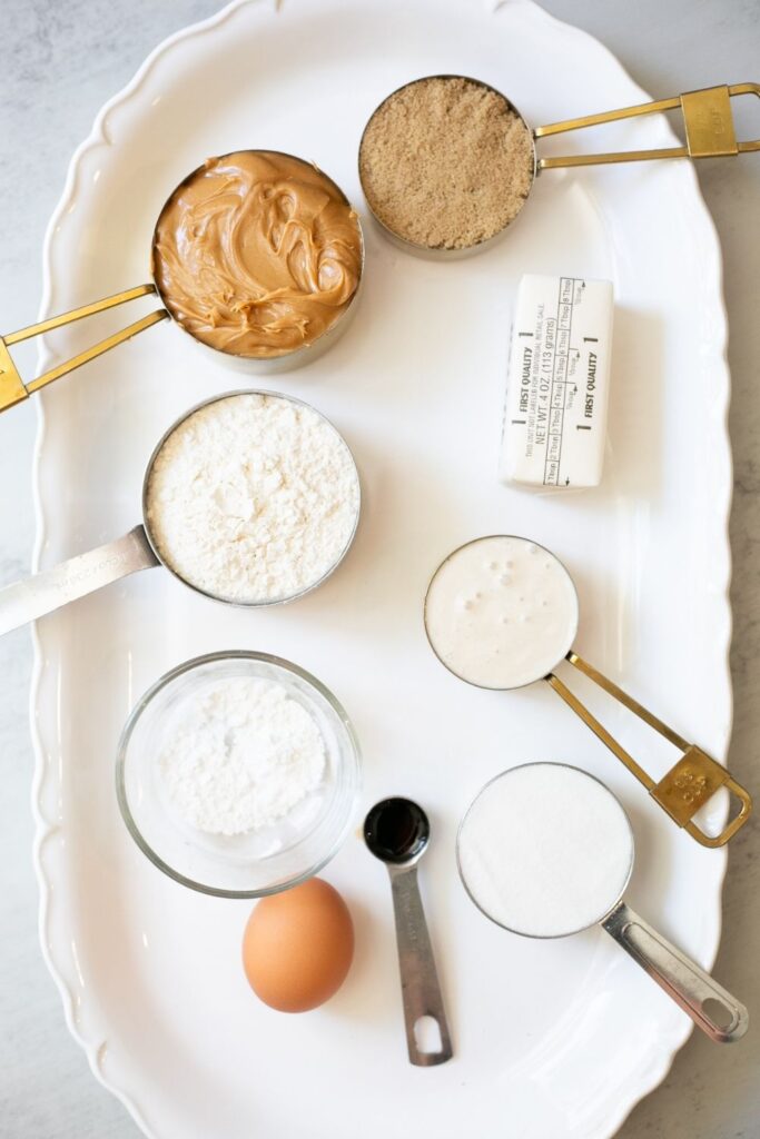 ingredients for sourdough discard peanut butter cookies on a tray: sourdough discard, natural peanut butter, butter, brown sugar, vanilla, flour, egg