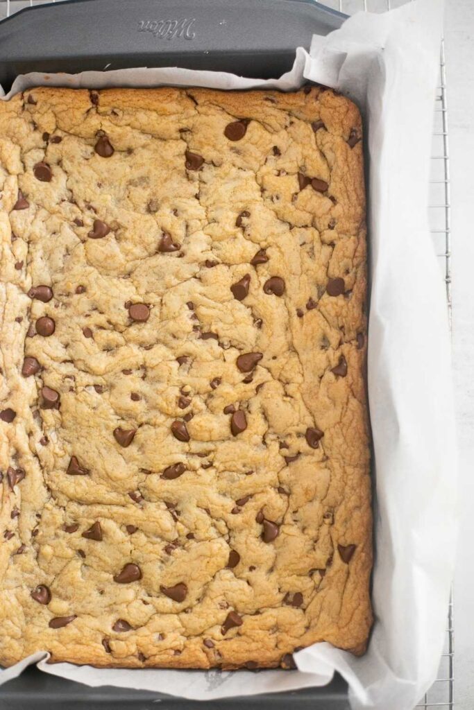 sourdough discard chocolate chip cookie bar dough in a 9x11 pan lined with parchment paper