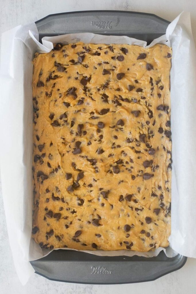 sourdough discard chocolate chip cookie bar dough in a 9x11 pan lined with parchment paper