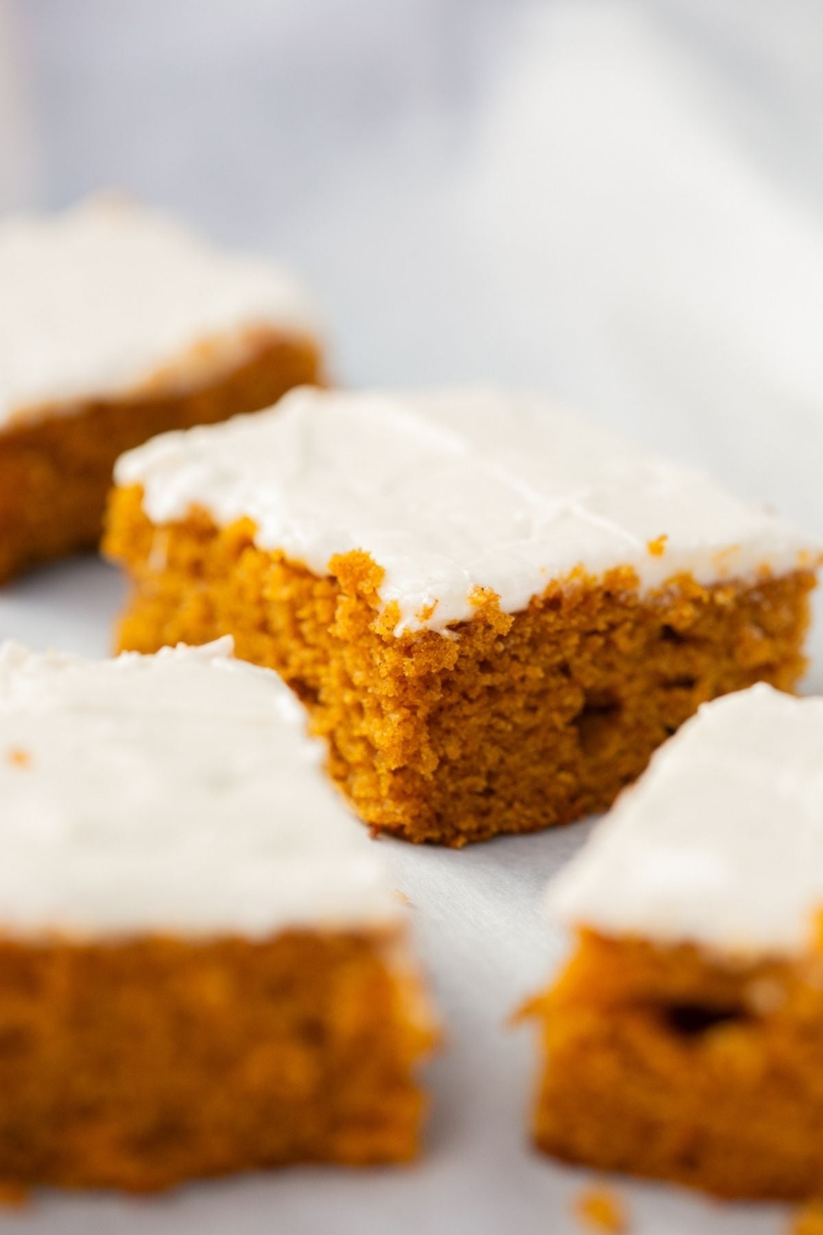 sourdough discard pumpkin bars with cream cheese frosting on a tray.