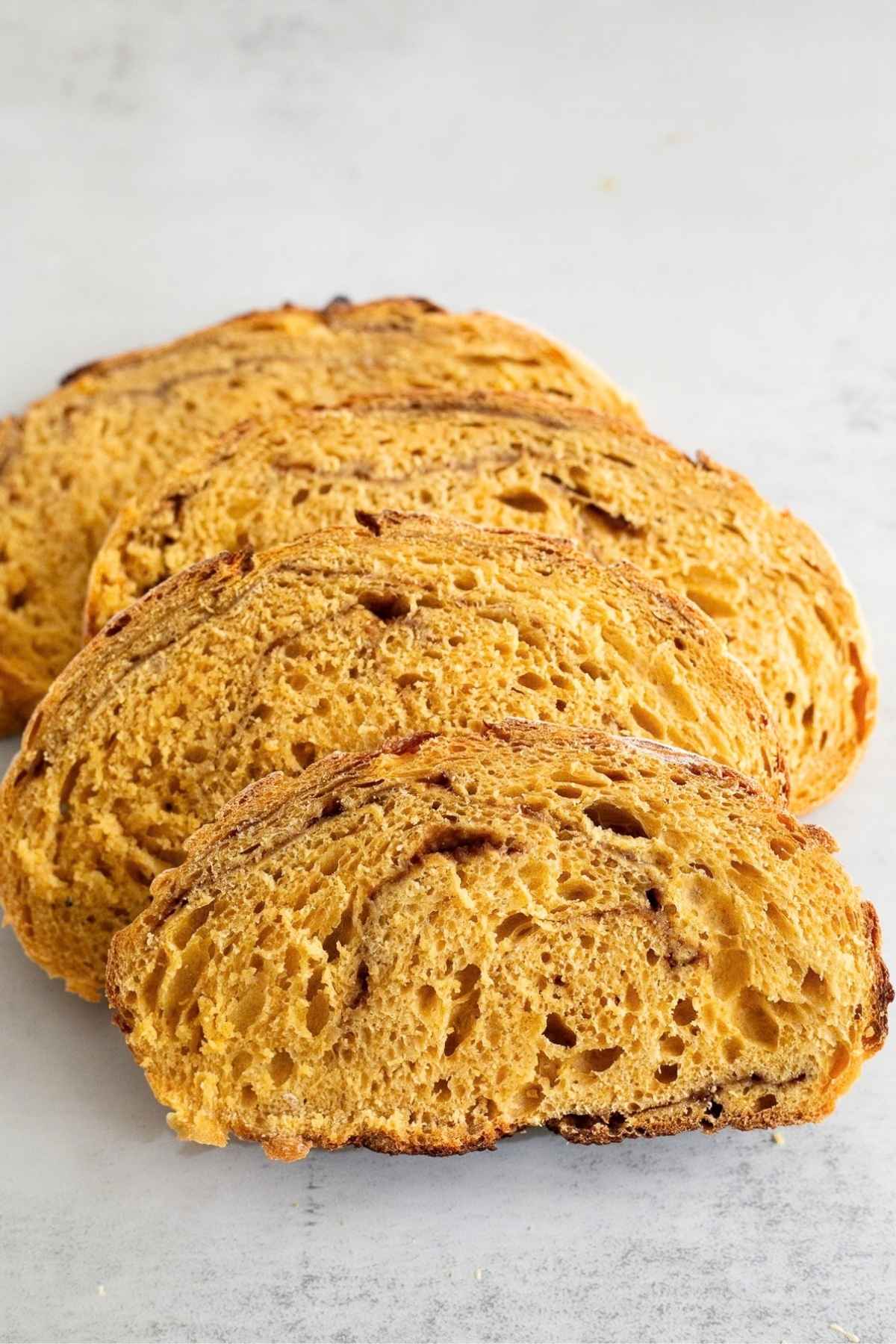 Slices of sourdough pumpkin bread on a table with a cinnamon swirl.