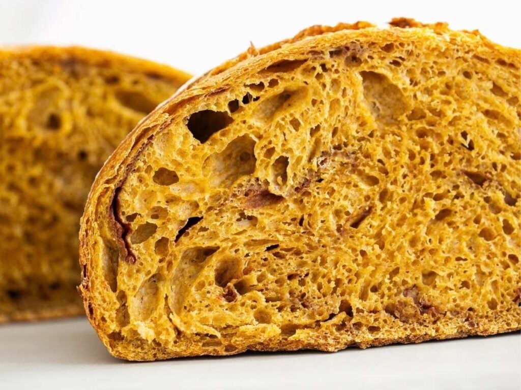 A slice of artisan sourdough pumpkin bread loaf on a table.